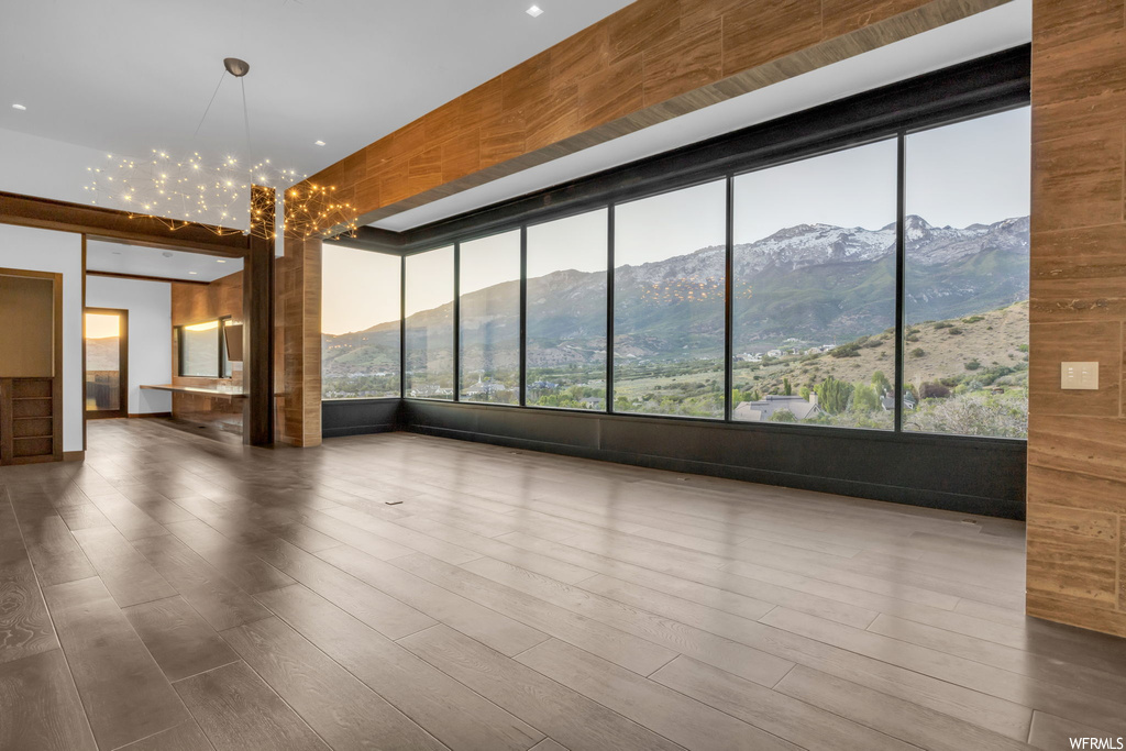 Empty room with dark hardwood floors, a mountain view, and an inviting chandelier