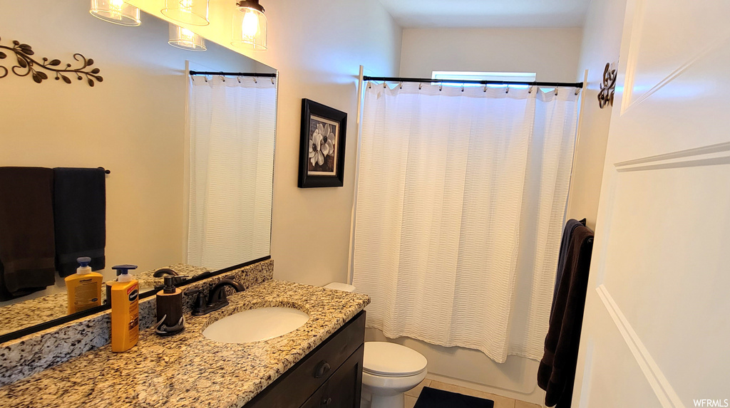 Full bathroom featuring tile flooring, toilet, vanity, and shower / bath combo with shower curtain