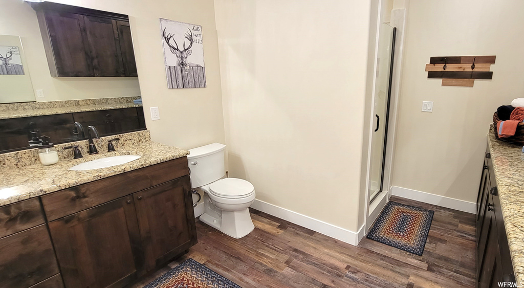 Bathroom featuring a shower with door, large vanity, hardwood flooring, and toilet