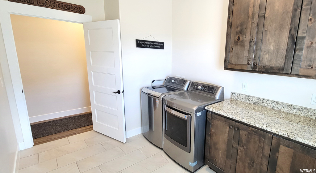 Laundry room with washer and clothes dryer, cabinets, and light tile floors