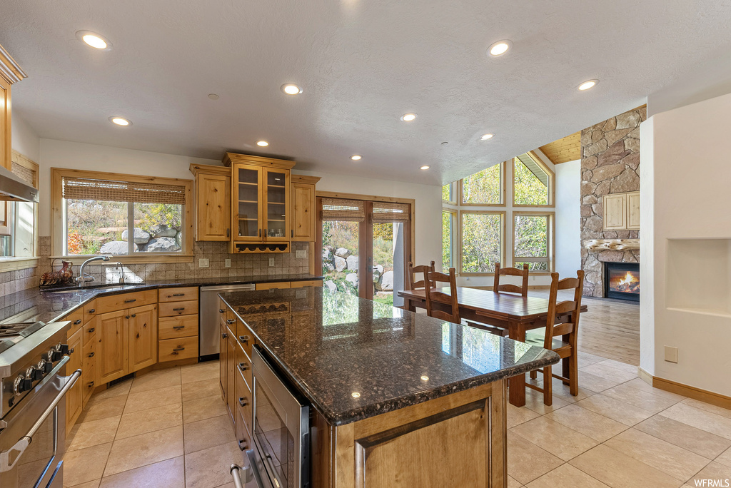 Kitchen featuring sink, a fireplace, backsplash, a kitchen island, and stainless steel appliances