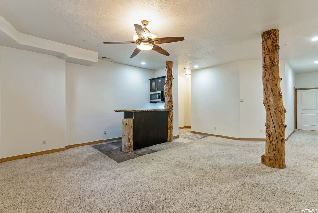 Unfurnished living room with light colored carpet and ceiling fan