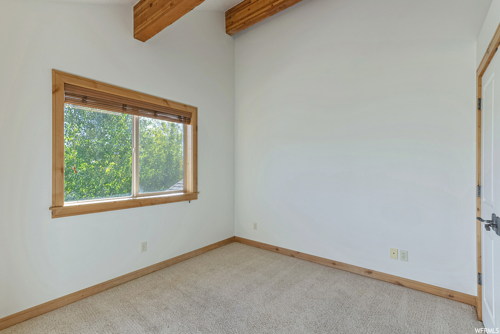 Spare room featuring light colored carpet and beam ceiling