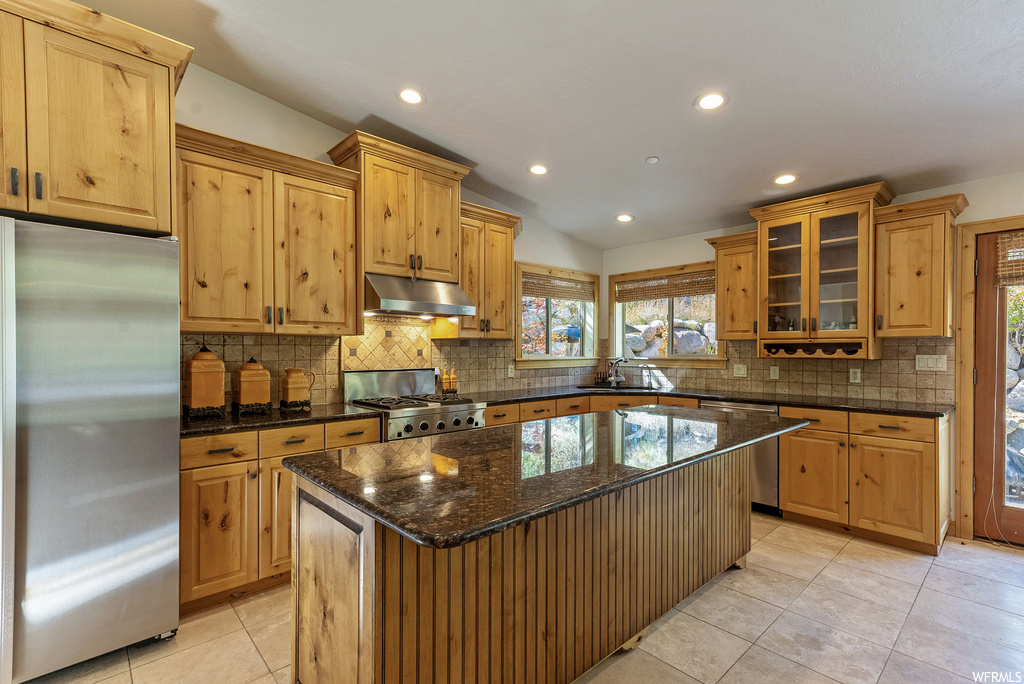 Kitchen with stainless steel appliances, a healthy amount of sunlight, and tasteful backsplash