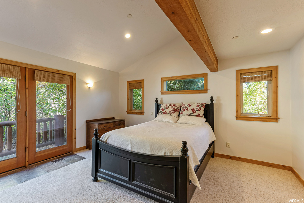 Bedroom featuring multiple windows, light colored carpet, vaulted ceiling with beams, and access to exterior