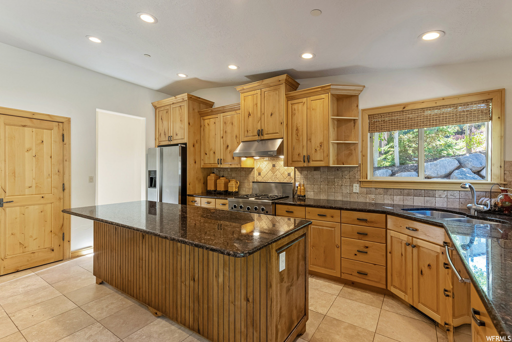 Kitchen with a kitchen island, tasteful backsplash, stainless steel fridge, light tile flooring, and sink