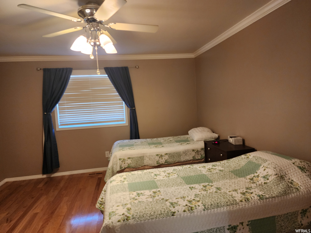 Bedroom with dark hardwood flooring, crown molding, and ceiling fan