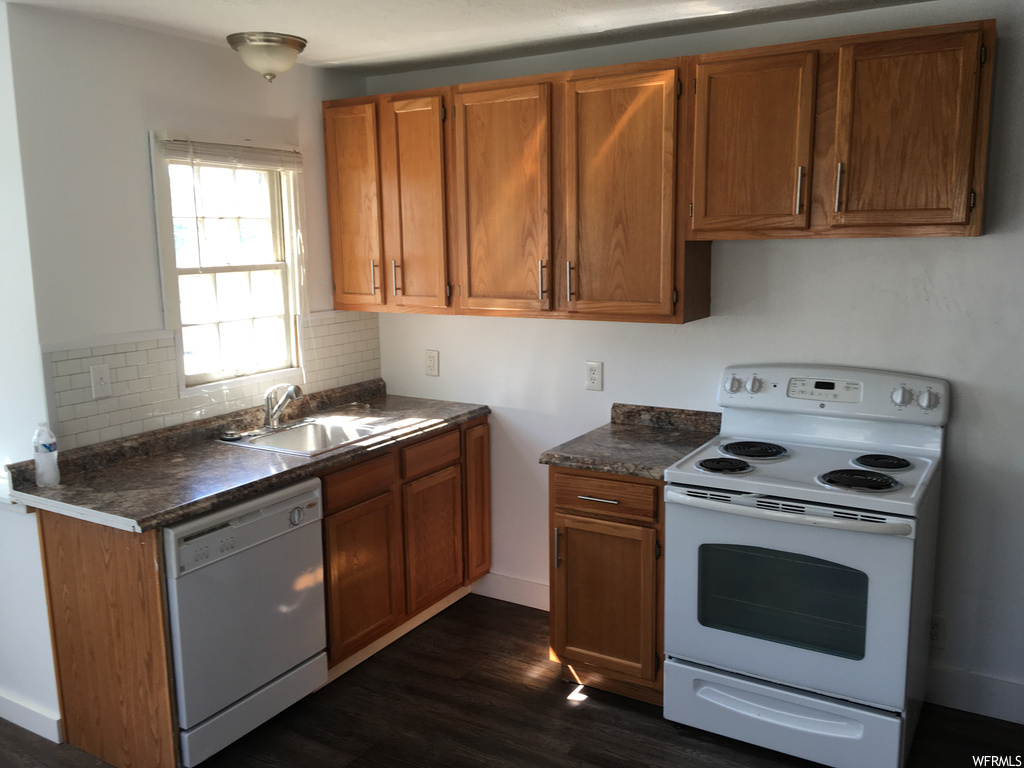 Kitchen featuring backsplash, white appliances, sink, and dark hardwood floors