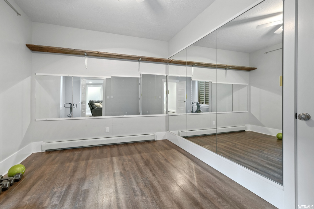Empty room featuring dark hardwood flooring and a baseboard heating unit