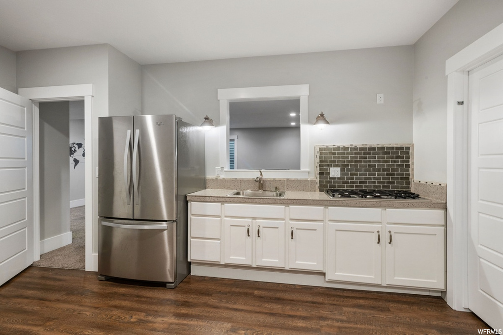 Kitchen with white cabinets, dark hardwood flooring, sink, and appliances with stainless steel finishes
