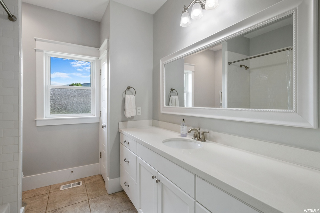 Bathroom featuring walk in shower, vanity with extensive cabinet space, and tile flooring