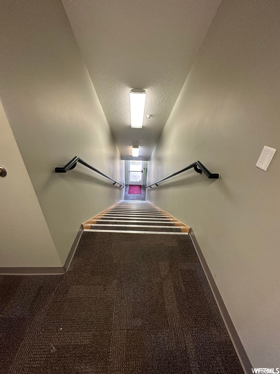 Stairway featuring dark carpet