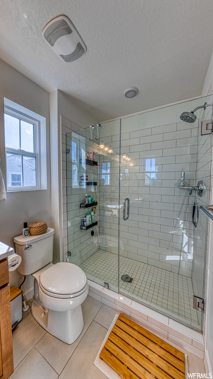 Bathroom with vanity, toilet, tile floors, and an enclosed shower