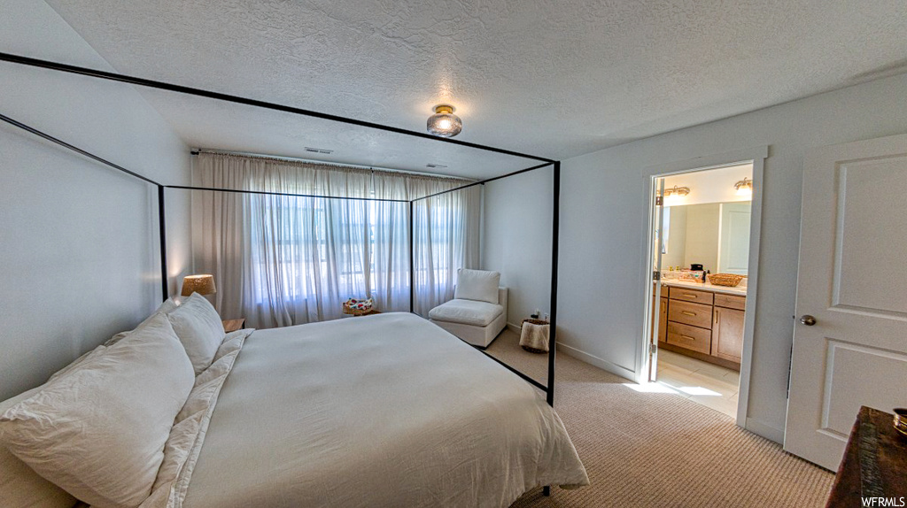 Carpeted bedroom featuring connected bathroom and a textured ceiling