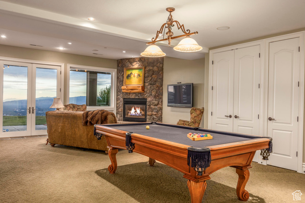 Game room featuring pool table, a fireplace, french doors, a mountain view, and light colored carpet