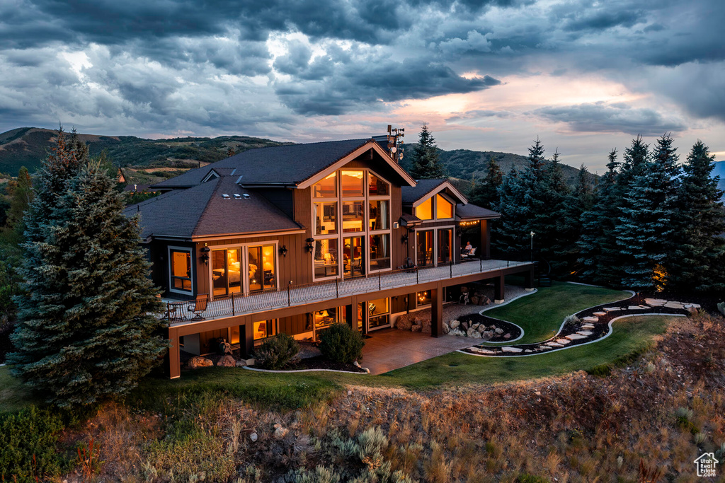 Back house at dusk featuring a patio and a mountain view