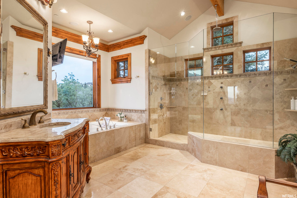Bathroom with oversized vanity, shower with separate bathtub, tile flooring, and a notable chandelier
