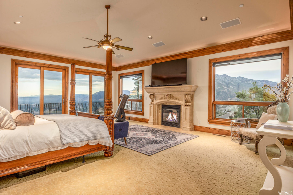 Carpeted bedroom featuring crown molding, ceiling fan, access to exterior, and a mountain view