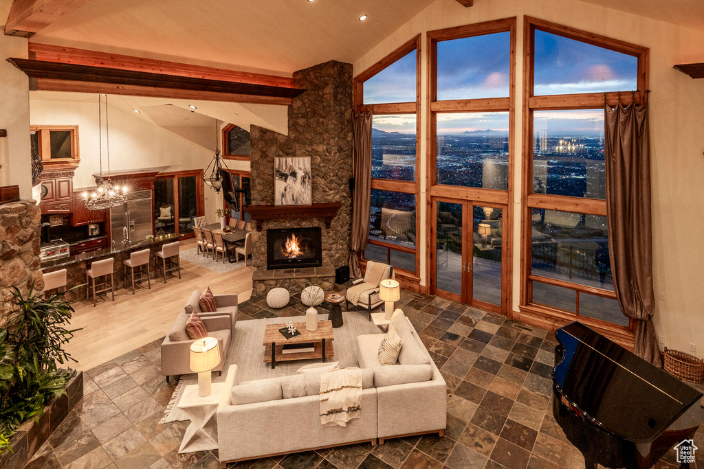 Living room with a notable chandelier, lofted ceiling with beams, wood-type flooring, and a fireplace