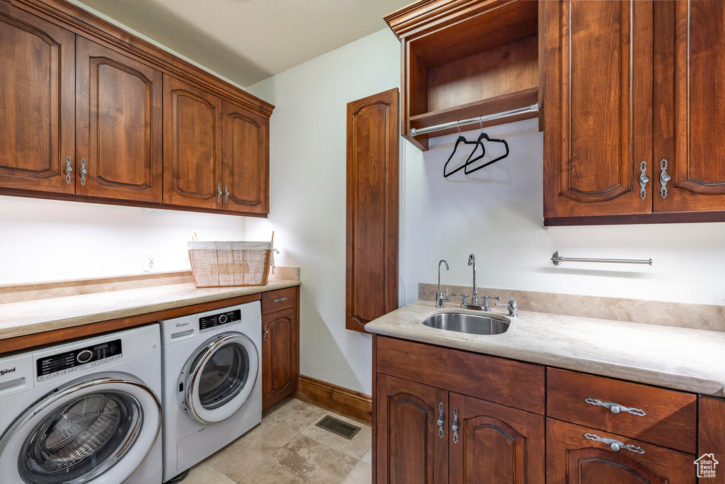 Clothes washing area featuring sink, independent washer and dryer, cabinets, and light tile floors
