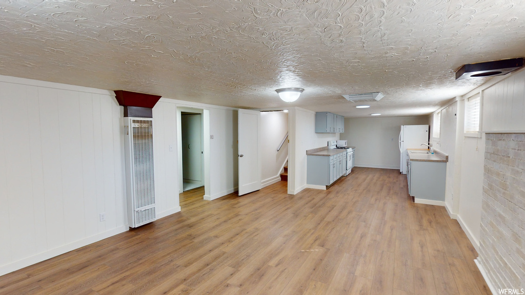 Basement featuring a textured ceiling, sink, and light hardwood flooring