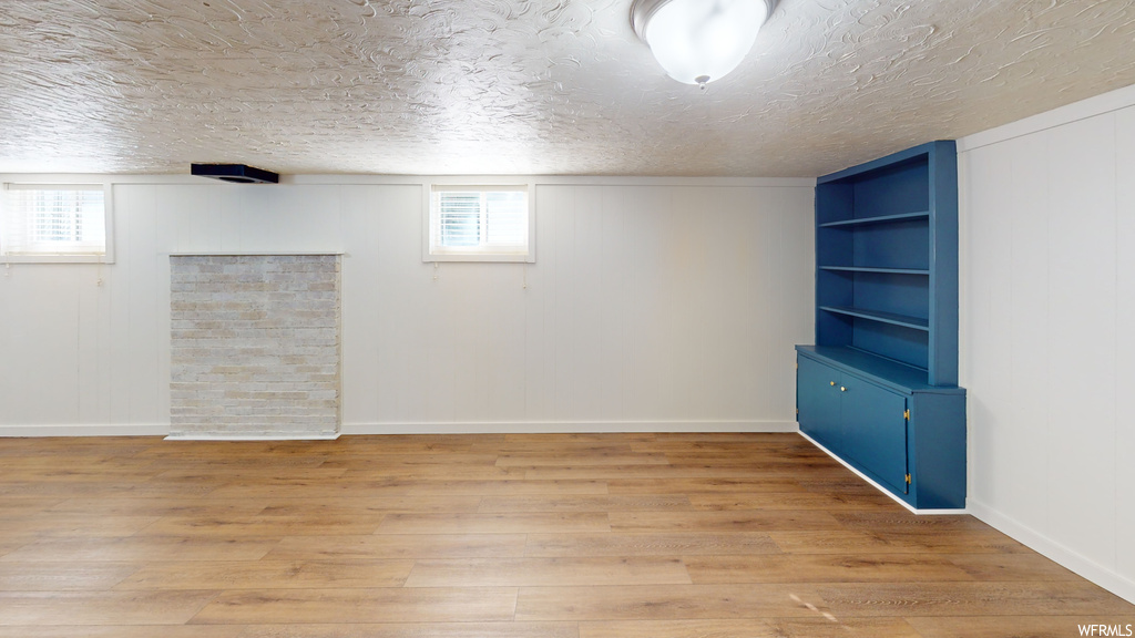 Empty room featuring light hardwood floors and a textured ceiling