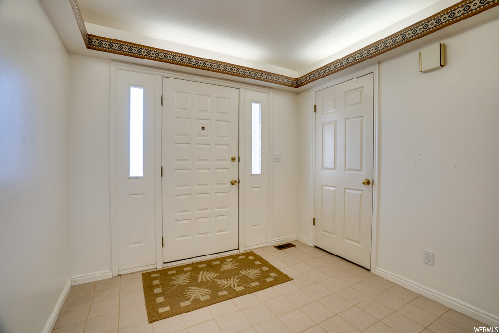 Foyer entrance with light tile floors and a healthy amount of sunlight