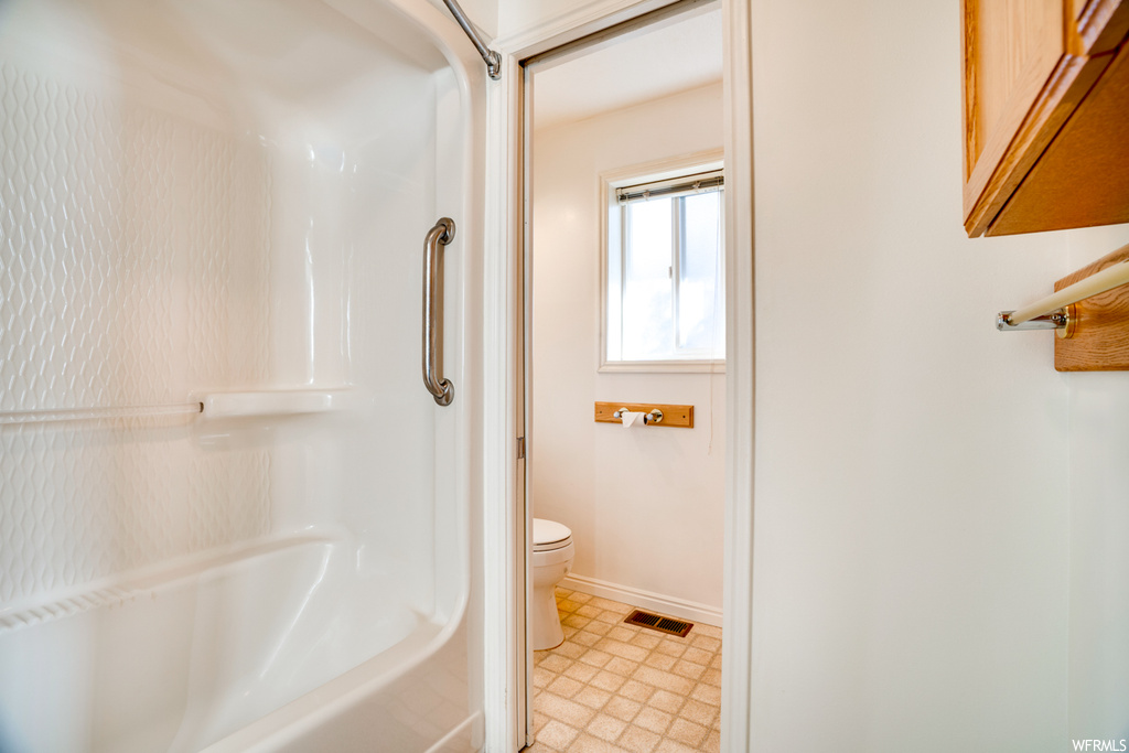 Bathroom with toilet, shower / bathtub combination, and tile flooring