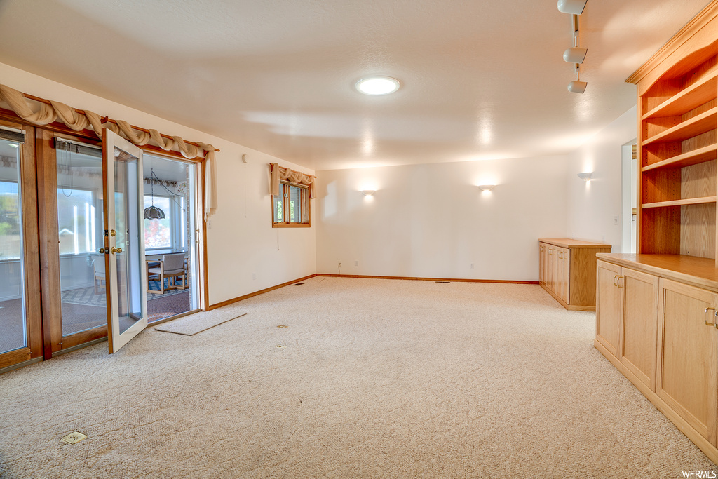 Carpeted empty room featuring rail lighting and french doors