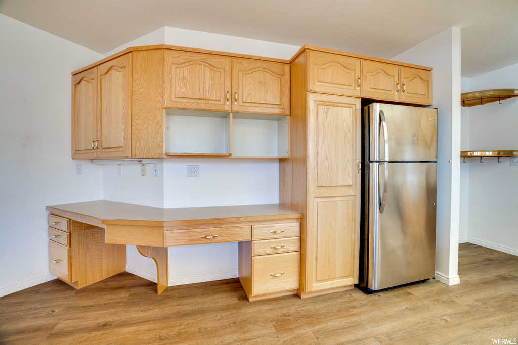 Kitchen with light brown cabinets, light hardwood flooring, and stainless steel refrigerator