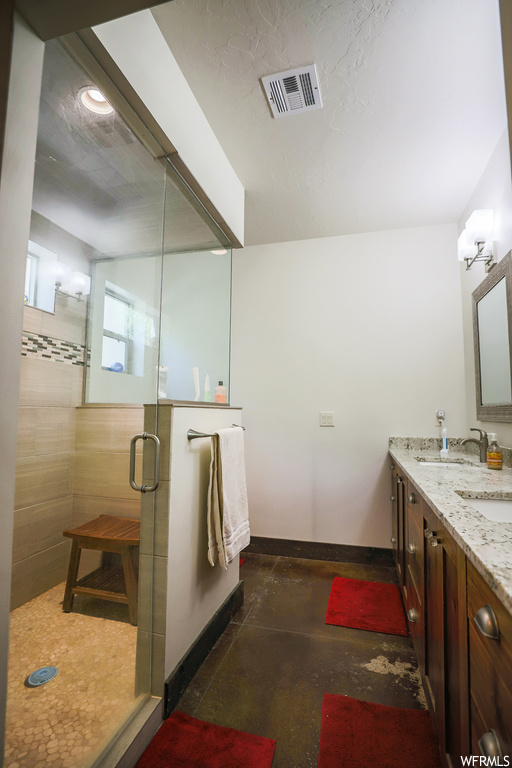 Bathroom with vanity, concrete floors, and an enclosed shower