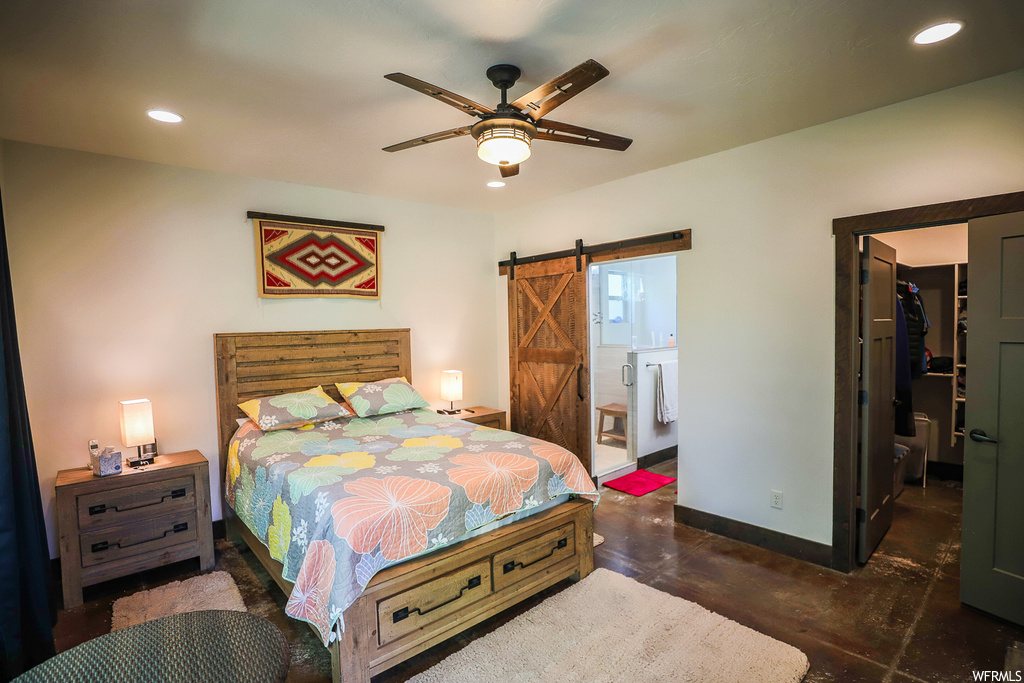 Bedroom featuring a spacious closet, a closet, ceiling fan, connected bathroom, and a barn door