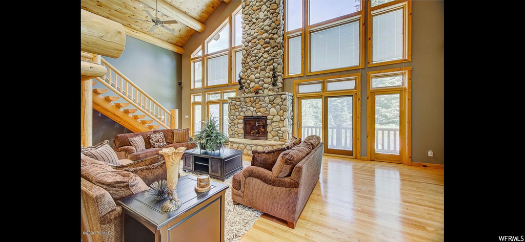 Hardwood floored living room with a fireplace, vaulted ceiling high, and beamed ceiling