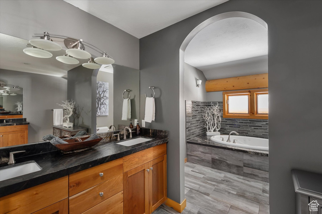 Full bath featuring tiled tub and double vanity