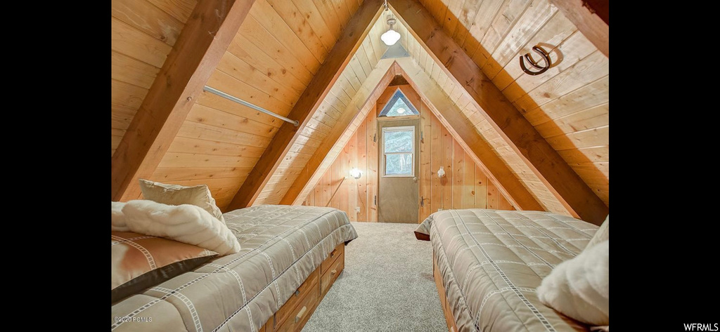 Bedroom with lofted ceiling, light carpet, wood ceiling, and wooden walls