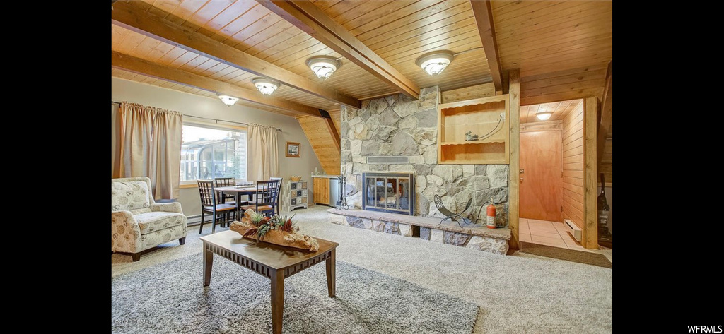 Carpeted living room featuring beam ceiling, wood walls, wooden ceiling, and a fireplace