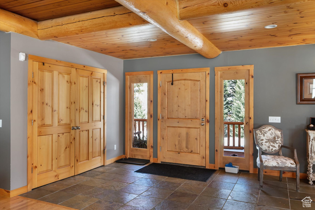 Foyer with wood ceiling, baseboards, and stone tile floors
