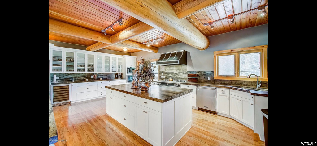 Kitchen featuring wall chimney range hood, wood ceiling, tasteful backsplash, and beam ceiling