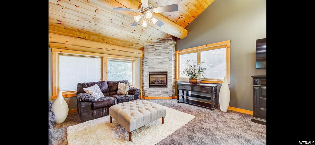 Living room with wood ceiling, light carpet, ceiling fan, and a stone fireplace