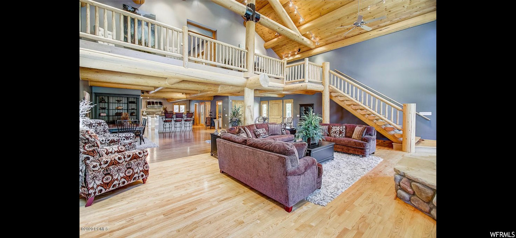 Hardwood floored living room featuring wood ceiling, vaulted ceiling high, and ceiling fan