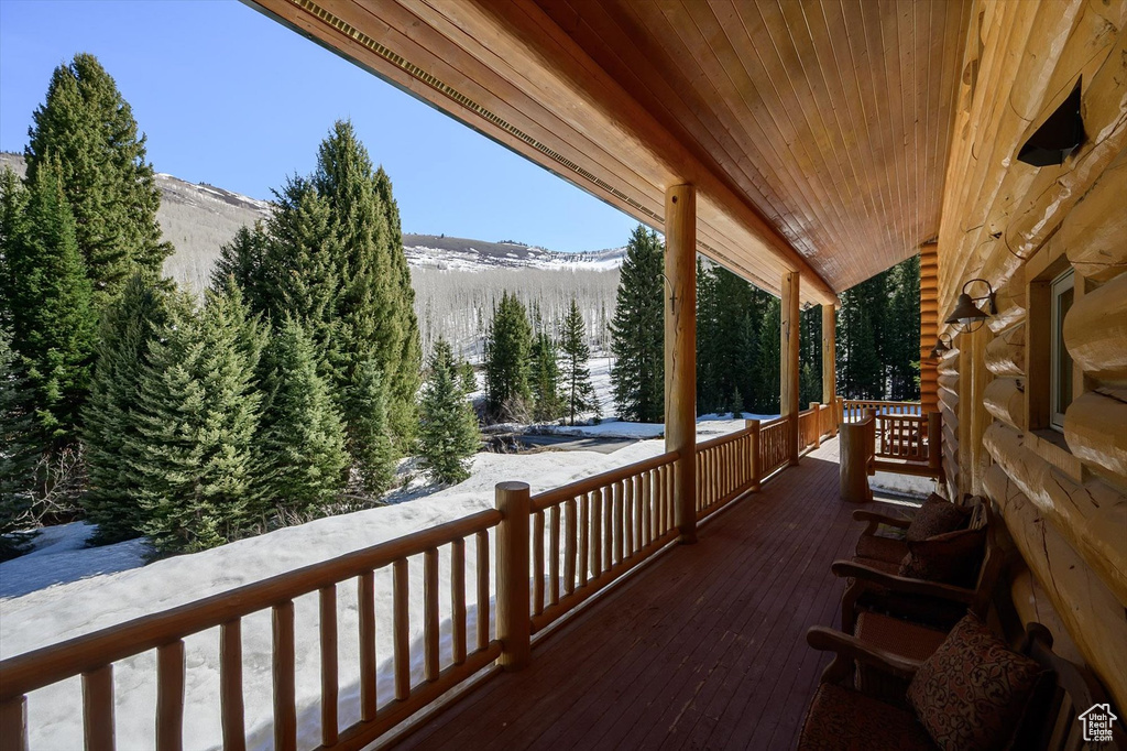 Snow covered deck featuring covered porch and a mountain view