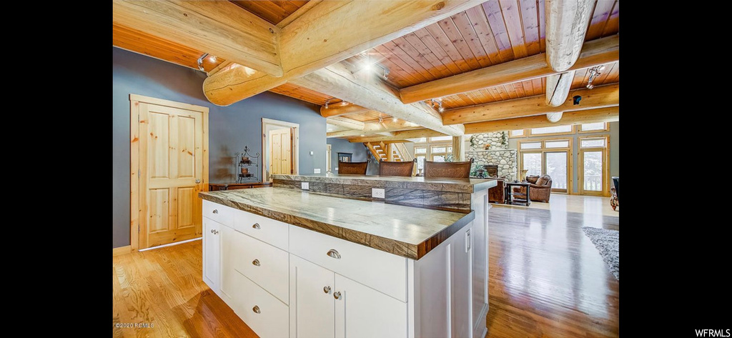 Kitchen featuring beam ceiling, white cabinets, light hardwood flooring, and wooden ceiling