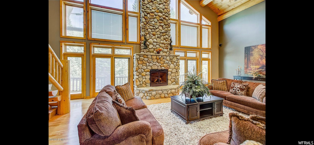 Living room featuring wood ceiling, a wealth of natural light, and a stone fireplace