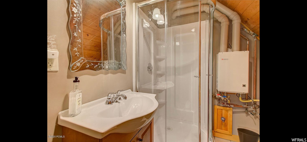 Bathroom featuring a shower with shower door, water heater, and oversized vanity