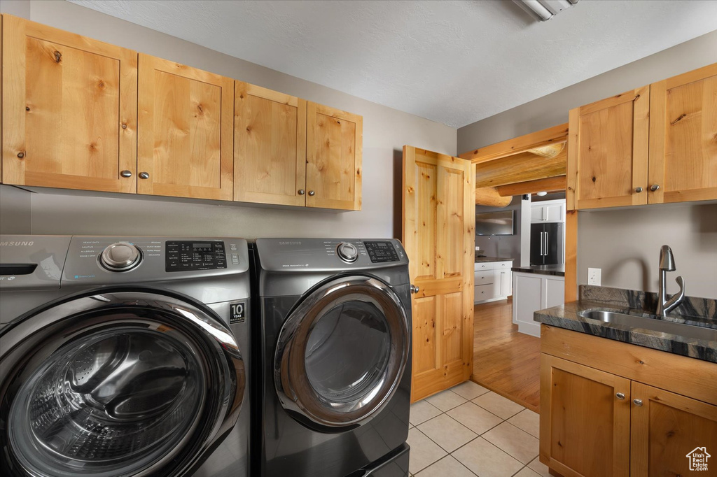 Laundry room with separate washer and dryer, cabinet space, and light tile patterned flooring