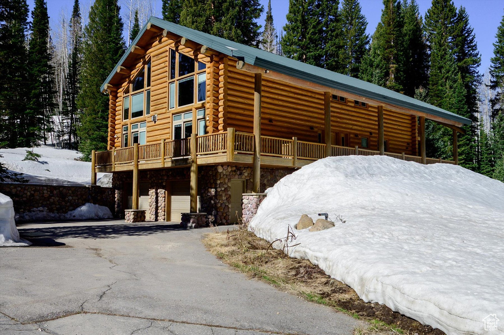View of home's exterior featuring log siding, stone siding, asphalt driveway, and an attached garage