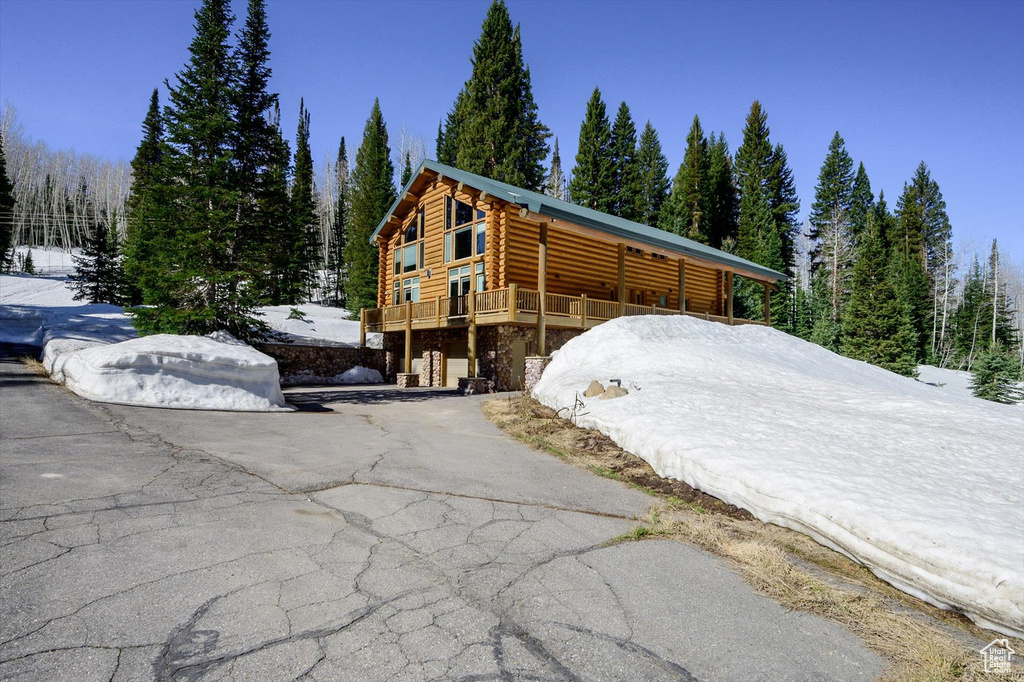 View of front of house featuring log siding, asphalt driveway, and a deck