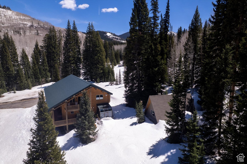 View of snow covered exterior featuring a view of trees and a mountain view