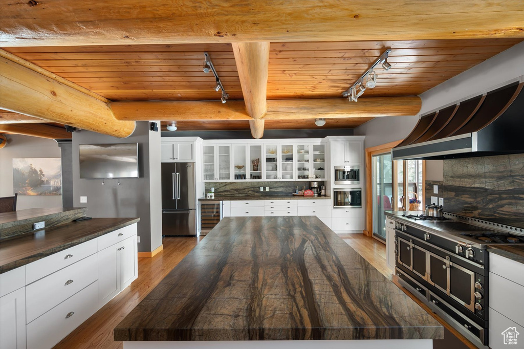Kitchen featuring high end fridge, track lighting, oven, wooden ceiling, and beverage cooler