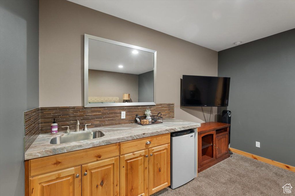 Kitchen with refrigerator, a sink, light carpet, decorative backsplash, and light countertops